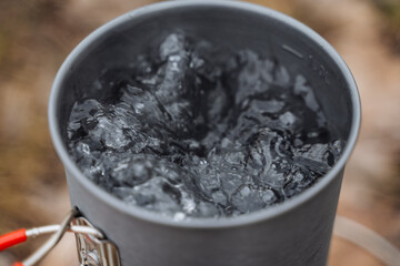 Boiling water in a pot, Shot close-up of water bubbles when heated, tourist pot, brewing tea, cooking on a hike.