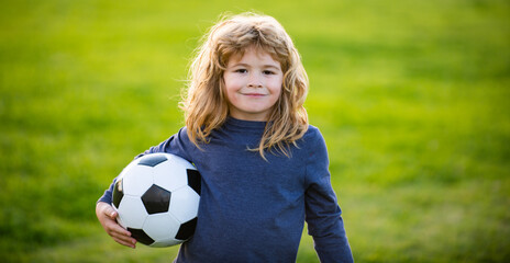 Young soccer player in sportswear with soccer ball. Cheerful little boy enjoy soccer, football sport games. Kid holding ball, closeup kids portrait. Portrait of child boy holds a soccer ball.