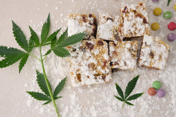 Craft sweets with cannabis on ivory background. Layout with marijuana leaves, candy confetti and powdered sugar, top view, flat lay.