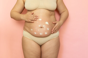 Cropped overweight woman in underwear applying moisturizer strokes gel to her abdomen. Belly fat removal. Wearing underwear, doing self massage to dehydrated skin. Cellulite obesity and striae problem