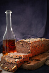 Organic sliced whole grain seeded bread on rustic wooden tray with extra olive oil in the bottle.