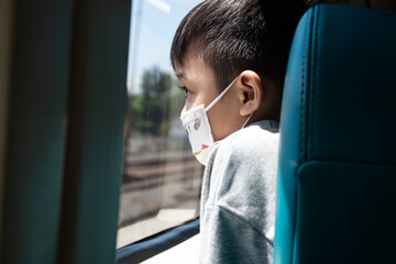 little boy looking in the mirror, straight hair and face mask on an out of focus background