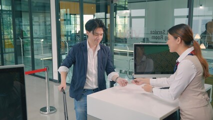 Male tourist in international airport at check-in counter checking staff giving passport and boarding pass from the attendant for he flight, travel and holiday season trip concept