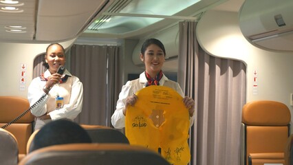 Asian stewardess safety explaining passengers prior to flight take off in airplane, air hostess...
