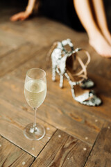 invitation card for bachelorette party, stylish black sandals with spikes, champagne glass and blurred legs on background, vertical, selected focus