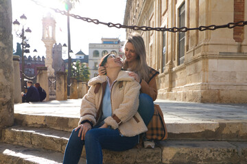 lesbian couple sitting on the steps of a pavement in a monumental square in old europe. They are very much in love and happy. Concept tourism and travel, lgtb. Rights and equality.