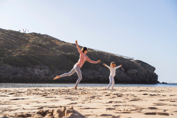 Happy mother and daughter having fun at beach on sunny day