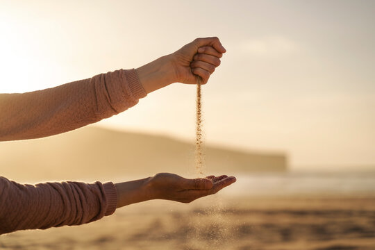 Sand falling out of closed fist at sunset