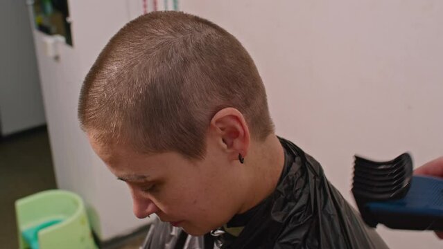 an adult man cuts a sad woman bald with a typewriter. Ukrainian female soldier.
