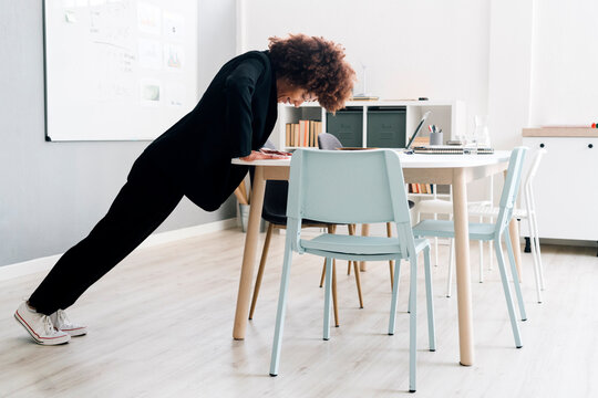 Businesswoman doing push-ups on desk in office