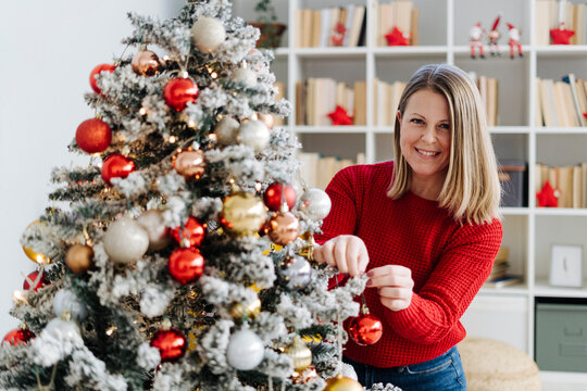 Happy woman decorating Christmas tree at home