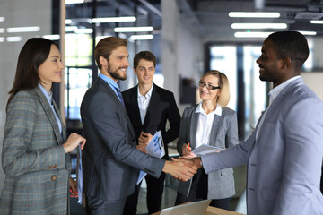 Confident business people shaking hands at workplace. - Powered by Adobe