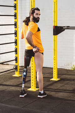 Amputated man with prosthetic leg standing in front of gymnastics bars