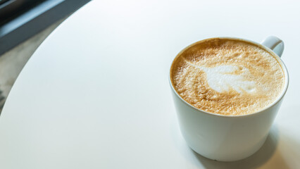 Coffee cup with milk and art shape on white table background.