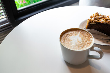 Coffee cup with milk and art shape on white table background.
