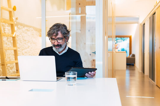 Freelancer using laptop sitting with tablet PC at home