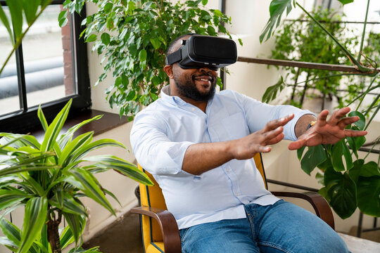 Smiling businessman wearing virtual reality simulator sitting on chair in office
