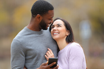 Happy couple holding phone looking each other in love