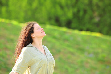 Relaxed woman breaths fresh air in a meadow