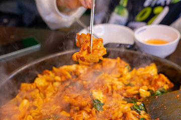 Korean traditional stir-fried spicy chicken, held in chopsticks
