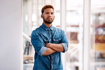 Confidence is everything. Cropped portrait of a handsome young male designer standing with his arms folded in the office.