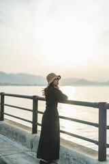 Fototapeta premium 夕暮れの海で黄昏れる女性