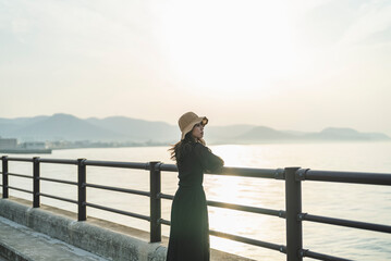 夕暮れの海で黄昏れる女性