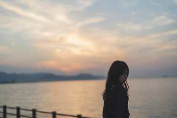 Fototapeta premium 夕暮れの海沿いで散策する女性