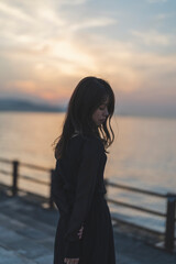 Fototapeta premium 夕暮れの海沿いで散策する女性