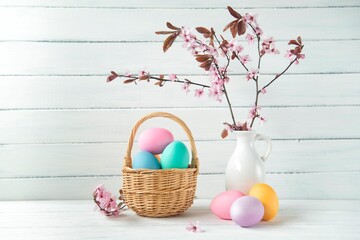 Easter eggs in a basket and pink cherry blossoms, Easter greeting card, wooden background