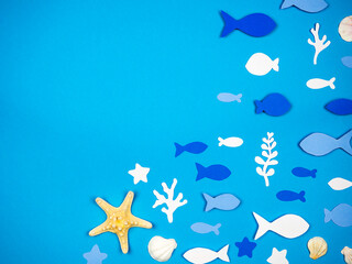 Starfish with seashells and fish made of paper on a blue background. Recreation Concept