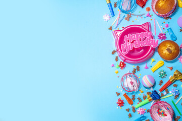 Pet happy birthday background with set different cats and kitty snack, food and toys, cat muzzle shape bowl, birthday cupcakes with happy birthday candles, accessories. Flatlay on blue background top 