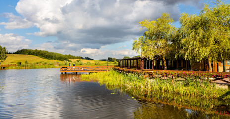 Panoramic view of Jezioro Wegleszynskie lake with wooded shores and and wooden jetty platform in Ostrzyce village in Kashubia region of Poland