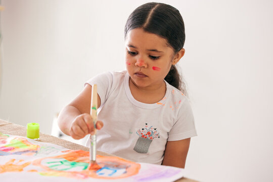 Encourage your children to be creative. Shot of an adorable little girl painting while sitting at a table.