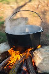Fish soup prepared over an open fire. Cooking fish soup over an open fire in a kettle. Cooking in hiking tourism and fishing