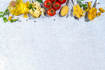 Various dried spaghetti, noodles, pasta set in spoons on white table background. Different shapes types raw italian pasta with herbs, olive oil, tomatoes, spices for cooking top view copy space