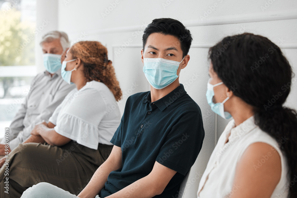 Poster Adhering to protocol for the safety of all. Shot of a group of people wearing face masks while sitting in a queue.