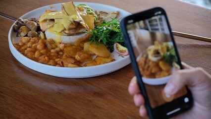 The blogger shoots his delicious lunch on his smartphone in order to share his life with his subscribers. Photographing food with a smartphone for social networks.