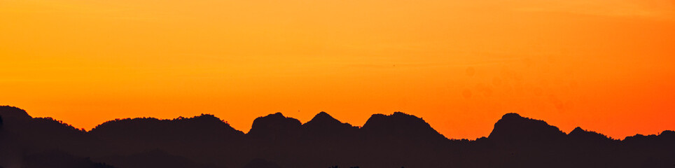 Dramatic  sunset landscape with orange sky, silhouettes of mountains