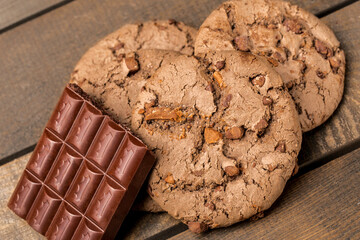 brown chocolate chip cookie large poan.  On a black background. Chocolate chip cookies with brown chocolate chips are placed on a wooden table.