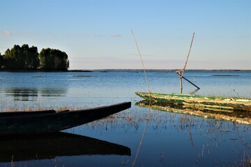 An old wooden fishing boat floating on the dark blue lake at evening time