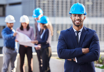 Ive got the team that can make it happen. Shot of a young businessman standing with his arms folded and wearing a hardhat while his colleagues stand behind him.