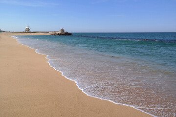 Fototapeta na wymiar White waves come over the sandy beach.