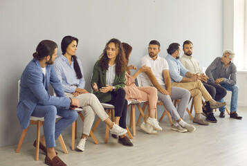 Groups of people of different ages talking to each other while waiting in line. Serious men and...