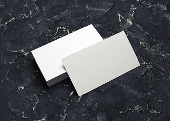 Photo of blank white business cards on black plaster background. Mock-up for branding identity....