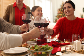 Family clinking glasses of wine at festive dinner, focus on hands. Christmas celebration