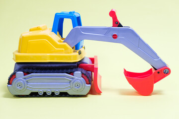 Plastic excavator car on yellow background. Construction machinery car for digging for toy store and children.