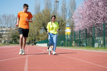 Obraz premium A guy, a girl and her beagle dog are running
