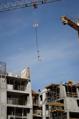 Prace budowlane z użyciem dźwigu oraz wiszącego paleciaka z widocznym budynkiem w tle © Clear Emotion