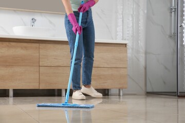 Woman cleaning floor with mop indoors, closeup. Space for text